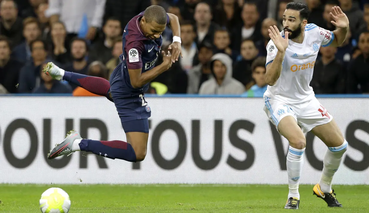 Pemain PSG, Kylian Mbappe (kiri) melompat saat diadang pemain Marseille, Adil Rami pada lanjutan Ligue 1 di  Velodrome Stadium, Marseille, (22/10/2017). PSG bermain imbang 2-2 melawan Marseille. (AP/Claude Paris)