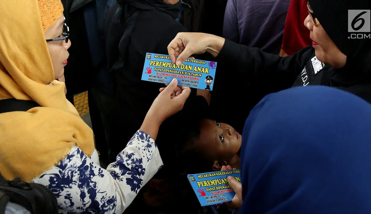 Petugas dari Polda Metro Jaya membagikan stiker kepada pengguna Kereta di Stasiun Tanah Abang, Jakarta, Kamis (21/12). Stiker ini bertuliskan informasi tentang pengaduan ketika terjadi kasus pelecehan seksual di ruang publik. (Liputan6.com/JohanTallo)