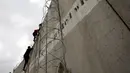 Sejumlah pria Palestina menggunakan tangga memanjat tembok Israel yang kontroversial saat akan salat Jumat pertama Ramadan di masjid Al-Aqsa, Yerusalem (10/5/2019). (Reuters/Mohamad Torokman)