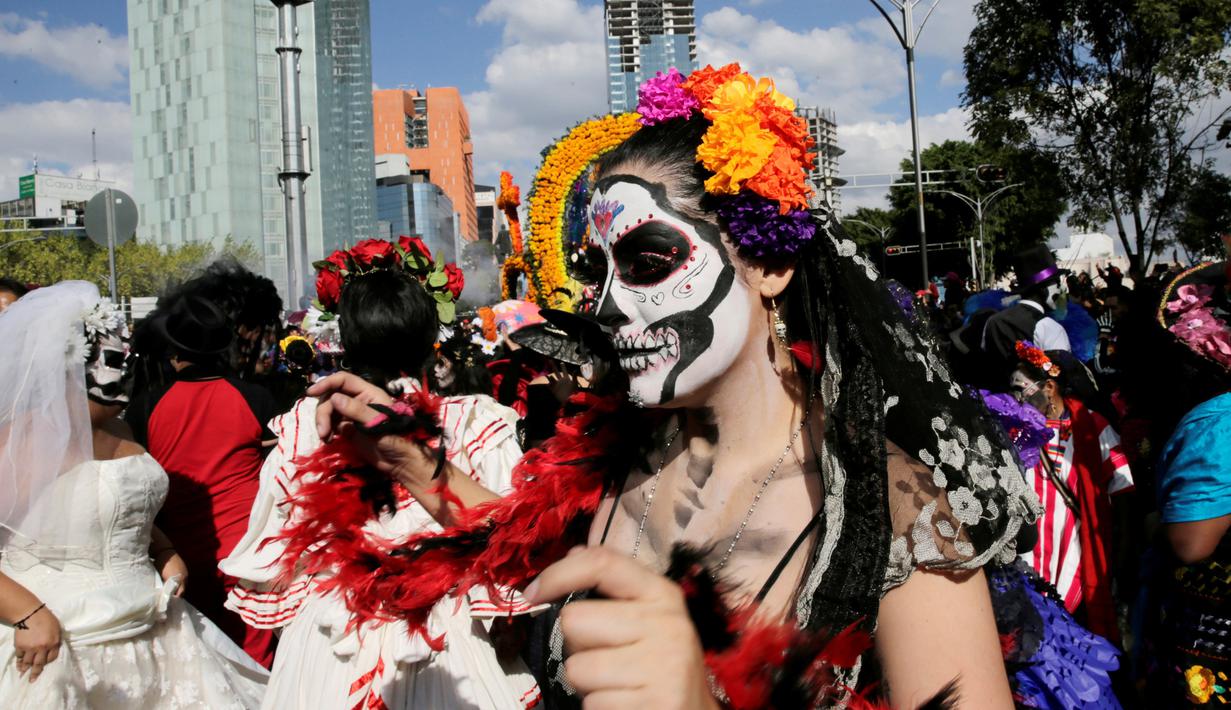 Seorang wanita menghias wajahnya saat parade "Day of the Dead" di Mexico City, Meksiko, Sabtu, (29/10). Festival Kematian bertujuan untuk mengenang dan menghormati orang-orang yang telah meninggal. (REUTERS / Carlos Jasso)