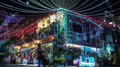Seorang pria berjalan dengan seekor anjing melewati sebuah rumah bertema Natal di Manila, Filipina (21/12/2022). Perayaan Natal tinggal menghitung hari, warga Manila antusias mengunjungi rumah yang didekor dengan ornamen dan hiasan Natal itu. (AFP/Jam Sta Rosa)