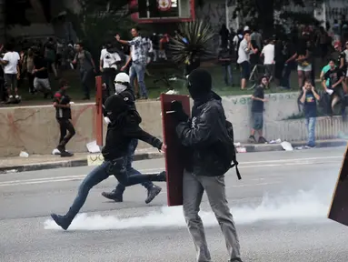 Seorang demonstran menendang gas air mata yang ditembakkan Polisi Anti Huru hara, Brasil, Jumat (8/1/2016). Pengunjuk rasa protes terhadap kenaikan tarif untuk bus kota di Sao Paulo. (Reuters/Nacho Doce)