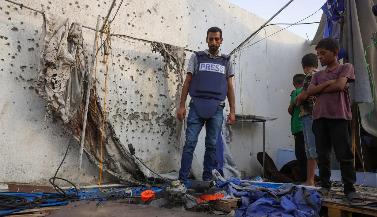 Anak-anak Palestina dan seorang jurnalis memeriksa tenda Al Jazeera yang hancur di Rumah Sakit Al-Shifa di Kota Gaza pada 11 Agustus 2025, menyusul serangan semalam oleh militer Israel. (BASHAR TALEB/AFP)
