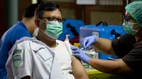 Seorang petugas bandara mendapatkan vaksinasi COVID-19 keempat atau booster kedua di kantor otoritas Bandara Ngurah Rai, dekat Denpasar, Bali, Senin (30/1/2023). Vaksinasi booster kedua ini menyasar 13.500 pekerja dari komunitas Bandara I Gusti Ngurah Rai. (SONNY TUMBELAKA / AFP)