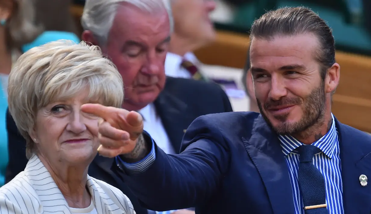 Aktor David Beckham berbincang dengan ibunya Sandra menyaksikan dari Royal Box pada hari kelima di Kejuaraan Tenis Wimbledon 2017 di London, Inggris (7/7). Beckham tampil dengan jas berwarna biru dan menggunakan kaca mata hitam. (AFP Photo/Glyn Kirk)
