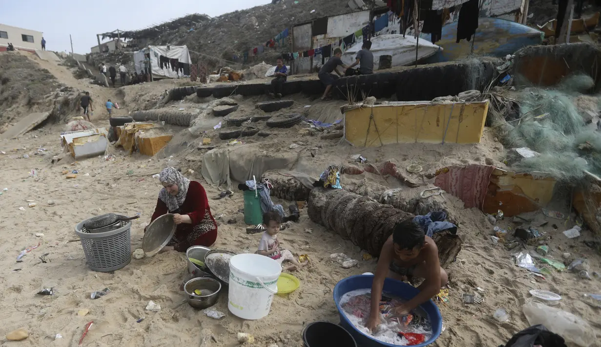 Warga Palestina menggunakan air laut untuk mandi dan membersihkan peralatan serta pakaian mereka akibat kekurangan air yang terus berlanjut di Jalur Gaza, di pantai Deir al-Balah, Jalur Gaza Tengah, Minggu, 29 Oktober 2023. (AP Photo/Mohammed Dahman)