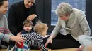 Perdana Menteri Inggris Theresa May bermain dengan bayi saat berkunjung ke pusat kesehatan di London, Inggris, Kamis (22/11). Theresa menjabat sebagai Perdana Menteri Inggris sejak 2016. (Andrew Matthews/Pool via AP)