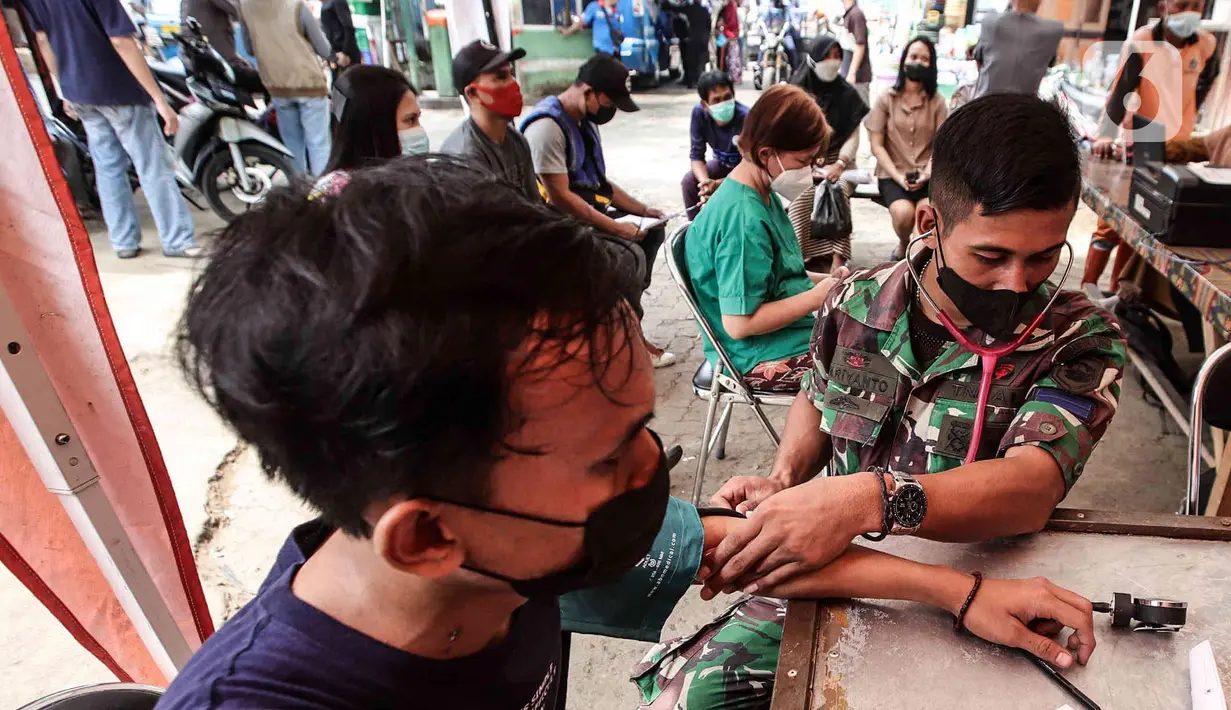 Anggota Marinir AL mengecek kesehatan warga sebelum vaksin booster di Pasar Palmerah, Jakarta, Selasa (19/4/2022). Satuan Tugas Penanganan Covid-19 merilis surat edaran yang mengatur pelaku perjalanan untuk keperluan mudik Idul Fitri 1443 H. (Liputan6.com/Herman Zakharia)
