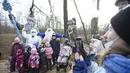 Dua staf yang mengenakan kostum karakter dongeng Rusia, Kakek Frost dan Putri Salju, berpose bersama anak-anak untuk difoto dalam pembukaan "Jalur Dongeng" di "Kediaman Kakek Frost" di Moskow, Rusia (18/11/2020). (Xinhua/Alexander Zemlianichenko Jr)
