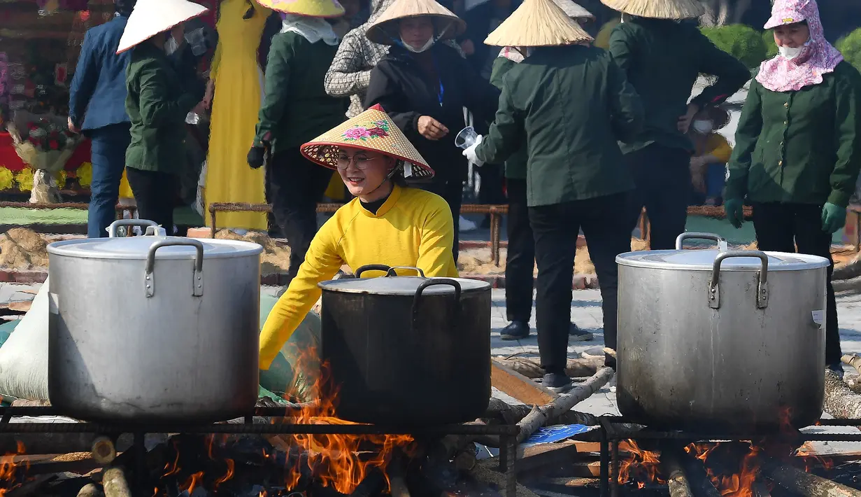 Seorang wanita sedang mengawasi panci mendidih berisi "Banh Chung" atau kue beras tradisional Vietnam untuk amal, menjelang Tahun Baru Imlek atau festival Tet di Pagoda Tam Chuc di provinsi Ha Nam (7/1/2023). Banh Chung adalah kelezatan khas Vietnam yang terbuat dari ketan, daging babi, dan kacang hijau yang dibungkus dengan daun pisang dan dimasak selama 10 jam. (AFP/Nhac Nguyen)