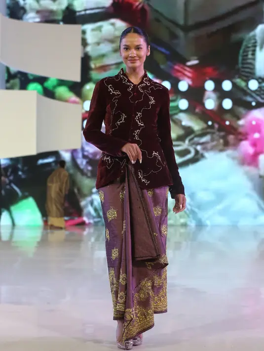 Hana Malasan elegan dengan kebaya maroon memiliki payet berhias dan benang sutra. Motif Batik tradisional yang didekonstruksi di seluruh tubuh. Kancing kain tersembunyi di bagian depan. Lengan panjang yang pas dan leher berbentuk V. [Adrian/Fimela]
