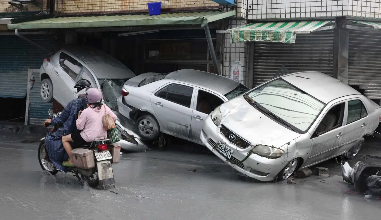 Sejumlah jalan di wilayah tersebut terendam dengan aliran air yang deras. Beberapa kendaraan hingga perabot rumah tangga turut hanyut terbawa aliran air bercampu lumpur. (I-Hwa Cheng/AFP)