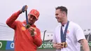 Pembalap Ferrari, Charles Leclerc berbincang sambil memegang medali emas Olimpiade Paris 2024 milik atlet balap sepeda track Belanda, Harrie Lavreysen menjelang Formula 1 GP Belanda di Sirkuit Zandvoort, Kamis (22/08/2024) waktu setempat. (AFP/John Thys)