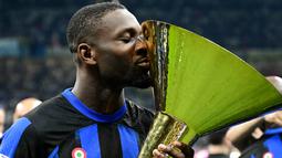 Pemain Inter Milan, Marcus Thuram, mencium trofi saat merayakan gelar juara Serie A di Stadion Giuseppe Meazza, (19/5/2024). Thuram meraih trofi Serie A di musim debutnya bersama Inter Milan. (AFP/Marco Bertorello)