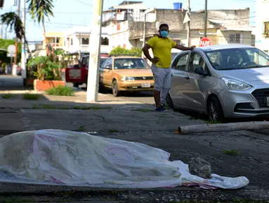 Seorang pria melihat ke arah jenazah yang tergeletak selama tiga hari di luar sebuah klinik di Guayaquil, Ekuador, Jumat (3/4/2020). Di Guayaquil, banyak dijumpai jenazah korban virus corona COVID-19 yang terlantar di jalanan. (Str/Marcos Pin/AFP)