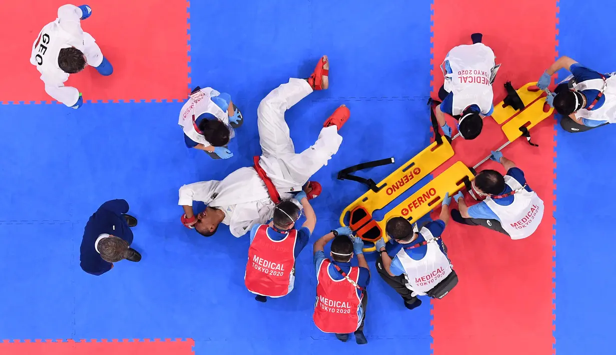 Atlet Jerman Jonathan Horne mendapat perawatan dari petugas medis setelah cedera saat melawan Gogita Arkania dari Georgia dalam pertandingan karate pada Olimpiade Tokyo 2020 di Nippon Budokan, Tokyo, Sabtu (7/8/2021). (Foto: AFP/Alexander Nemenov)