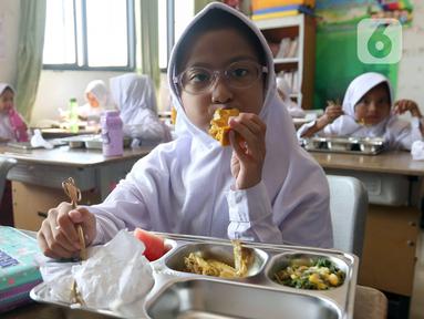 Seorang siswi sekolah dasar sedang menikmati menu makan bergizi gratis di Sekolah Dasar Negeri 01&02, Susukan, Jakarta, Senin (6/1/2025). (Liputan6.com/Herman Zakharia)