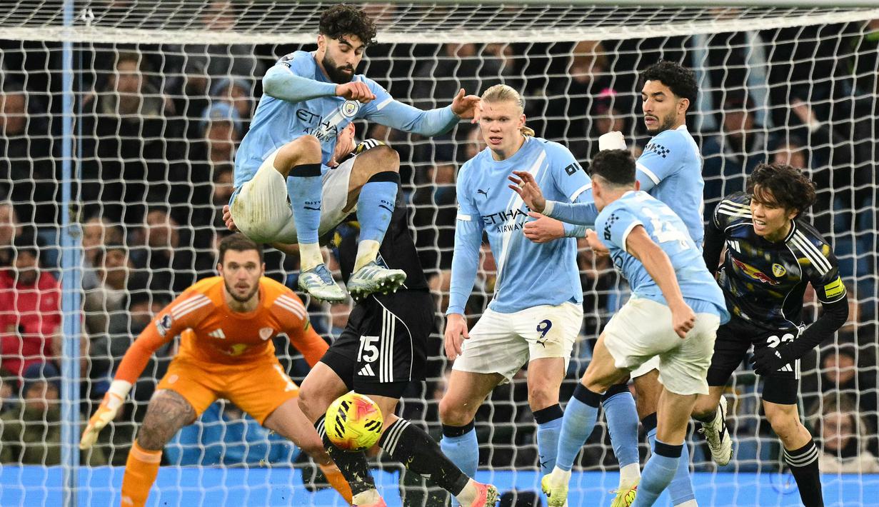 Pemain Manchester City, Josko Gvardiol, melakukan aksi loncat saat Phil Foden melepaskan tendangan ke gawang Leeds United pada pekan ke-13 Premier League 2025/2026 di Etihad Stadium, Sabtu (29/11/2025) malam WIB. (AFP/Oli Scarff)