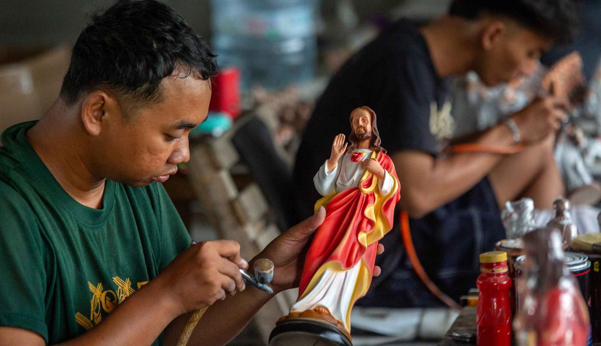 Para pekerja menyemprotkan cat ke patung-patung rohani di bengkel kerajinan Studio Malta Jaya di Bantul, Yogyakarta, pada Kamis 18 Desember 2025. Jelang perayaan Natal 2025, kesibukan terlihat di bengkel kerajinan Studio Malta Jaya di Bantul, Yogyakarta. (DEVI RAHMAN/AFP)