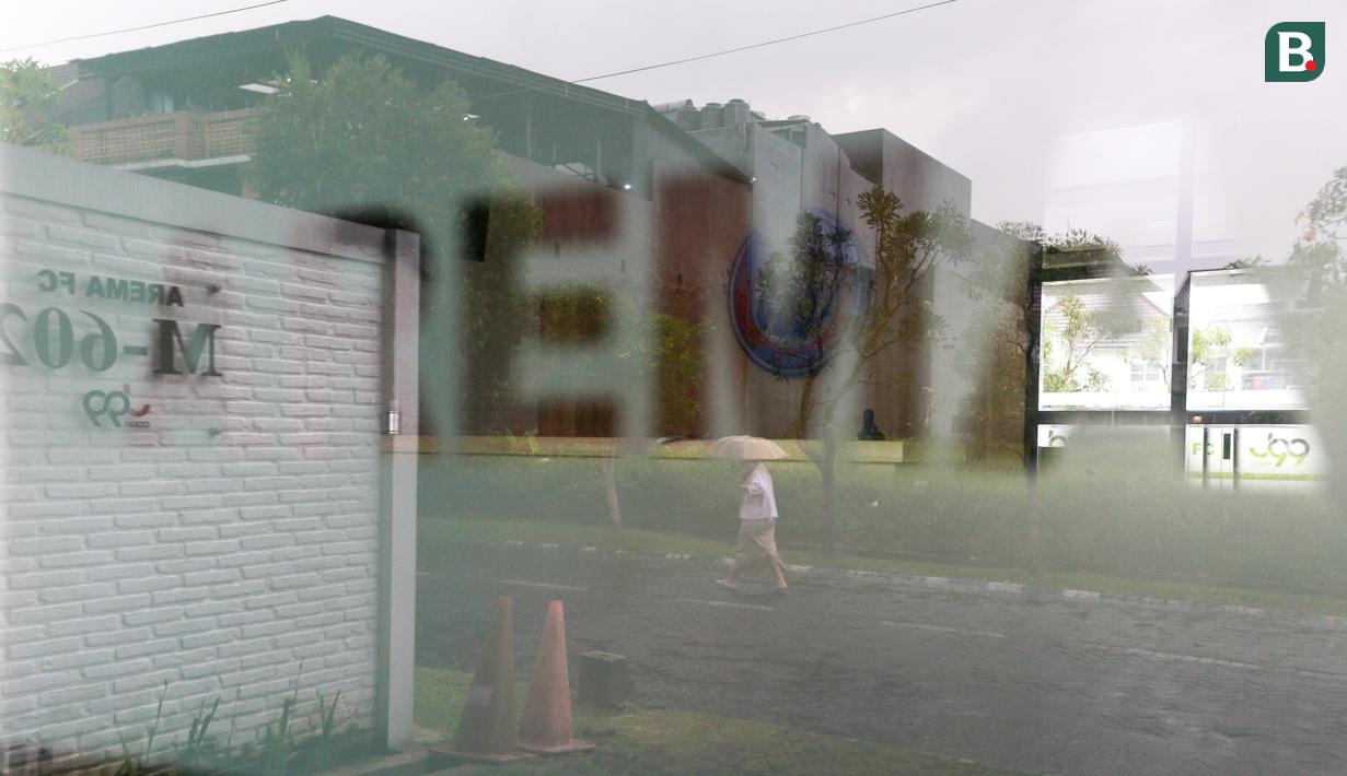 <p>Refleksi seorang warga yang tengah melintasi mes Arema FC yang terletak di Lowokwaru, Kota Malang, Minggu (09/10/2022). (Bola.com/Bagaskara Lazuardi)</p>