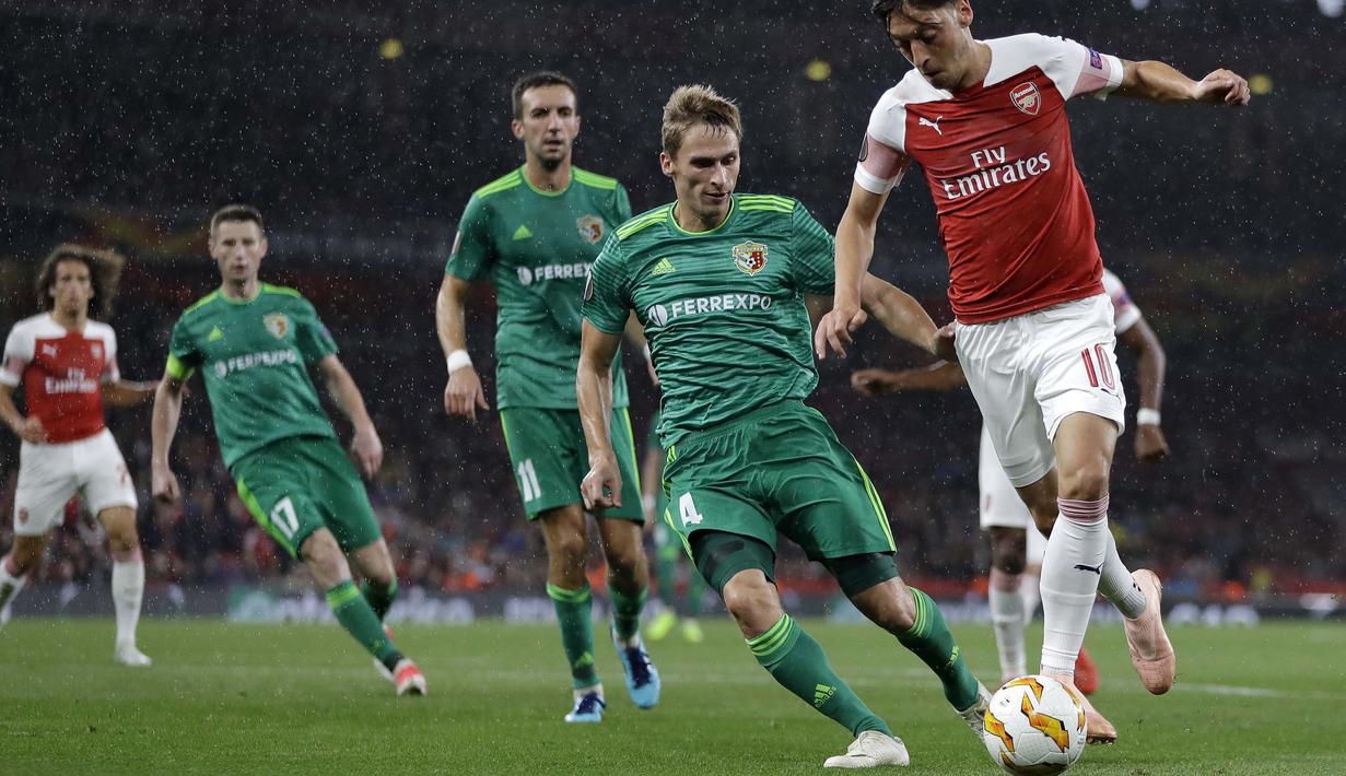 Pemain Vorskla, Igor Perduta, menjaga pergerakan gelandang Arsenal, Mesut Ozil, pada laga Liga Europa di Stadion Emirates, London, Kamis (20/9/2018). Arsenal menang 4-2 atas Vorskla. (AP/Kirsty Wigglesworth)