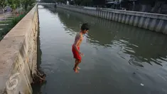 Seorang anak melompat ke anak Kali Ciliwung di Jakarta, Rabu (13/7). Bersihnya kali yang berada di Ibu Kota itu dimanfaatkan anak-anak sekitar untuk berenang sambil mengisi waktu libur sekolah. (Liputan6.com/Immanuel Antonius)