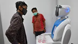 Teknisi mendengarkan robot Amy saat simulasi membantu petugas medis dalam menangani pasien virus corona COVID-19 di Rumah Sakit Pertamina Jaya (RSPJ), Jakarta, Kamis (16/4/2020). Amy akan digunakan untuk membawa makanan, obat, dan segala kelengkapan lain untuk pasien. (ADEK BERRY/AFP)