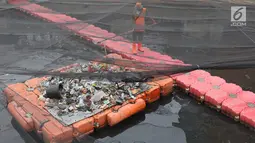Petugas membersihkan Kali Item yang tertutup kain waring atau jaring di Kemayoran, Jakarta, Minggu (4/11). Sampah plastik, botol mineral, kaleng dan bungkus rokok bertebaran di waring yang membentang di atas Kali Item. (Liputan6.com/Immanuel Antonius)