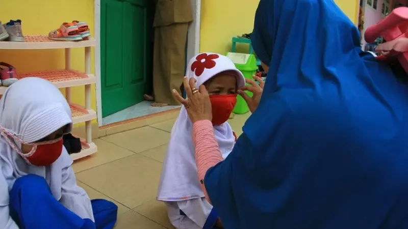 Guru memasangkan masker ke anak TK karena kabut asap di Pekanbaru sangat tidak sehat.