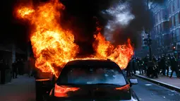 Mobil limusin yang dibakar pengunjuk rasa selama protes pelantikan Presiden Donald Trump di Washington, DC, AS, (20/1). Donald Trump resmi menjadi Presiden Amerika Serikat yang ke-45 mengantikan Barack Obama. (AP Photo/John Minchillo)