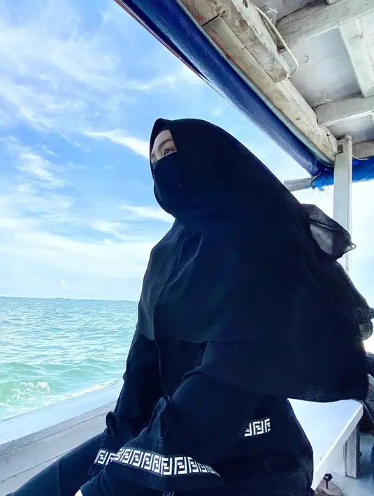 Ria Ricis mengunggah potret dirinya sedang duduk di atas kapal. Ia terlihat mengenakan busana terusan hitam. Mengenakan kerudung serda cadar senada pun membuatnya menuai pujian. (Liputan6.com/IG/@riaricis1795)