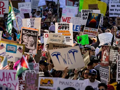 Para pengunjuk rasa mengangkat pamflet selama protes nasional “Hands Off!” terhadap Presiden AS Donald Trump dan penasihatnya, CEO Tesla Elon Musk, di pusat kota Los Angeles, Amerika Serikat pada 5 April 2025. (ETIENNE LAURENT/AFP)