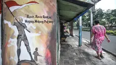 Warga melintas di depan mural bertemakan Pancasila di Kampung Pancasila kawasan Galur, Johar Baru, Jakarta, Selasa (1/6/2021). Kelurahan Galur membuat Kampung Pancasila yang dihiasi mural sebagai bentuk mengingatkan masyarakat akan Pancasila sebagai dasar negara. (merdeka.com/Iqbal S. Nugroho)