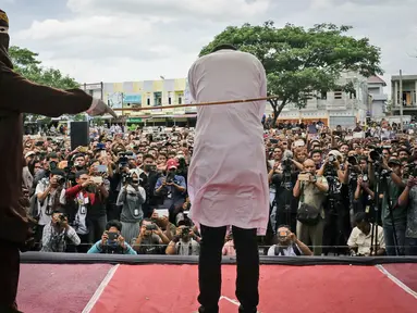 Petugas menyabetkan rotan ke punggung seorang terpidana kasus liwath alias gay di Banda Aceh, Indonesia, (23/5). Eksekusi hukuman cambuk ini digelar terbuka di hadapan publik. (AP Photo / Heri Juanda, File)