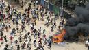 Para pengunjuk rasa berlari ke arah petugas polisi anti huru hara saat unjuk rasa massal di Kibera Slums, Nairobi, Senin, 27 Maret 2023. (AP Photo/Brian Inganga)