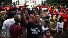 Warga berfoto dengan latar belakang anggota Paspampres yang melakukan prosesi pergantian jaga Istana Kepresiden di depan Istana Merdeka, Minggu (28/8). Seremoni pergantian pasukan ini mengundang perhatian warga. (Liputan6.com/Faizal Fanani)