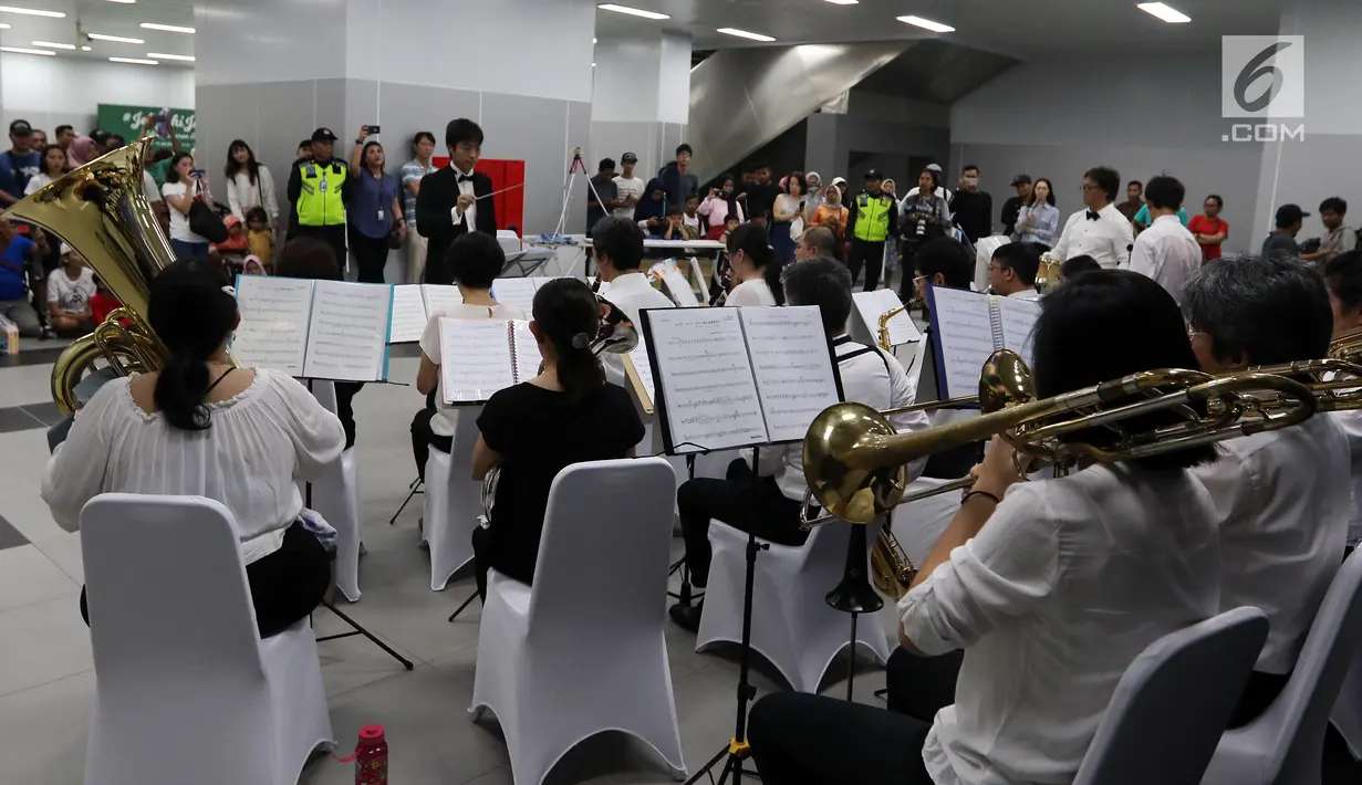 Penumpang Moda Raya Terpadu (MRT) melihat penampilan Orkes Tiup Jepang Jakarta di Stasiun Bundaran HI, Minggu (21/7/2019). Aksi Orkes Tiup Jepang yang terdiri dari instrumen tiup, kuningan dan perkusi oleh warga Jepang yang tinggal di Jakarta ini merupakan hiburan gratis. (Liputan6.com/Johan Tallo)