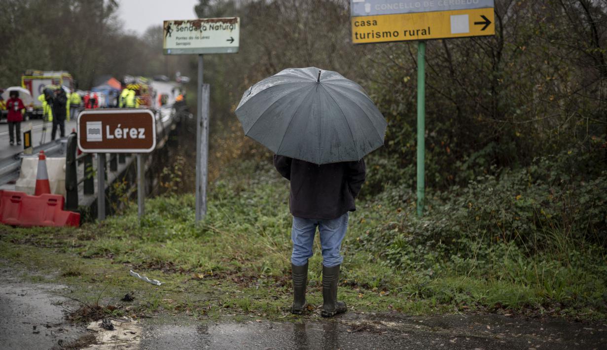 Seorang warga melihat saat layanan darurat sedang bekerja di sebuah jembatan di atas sungai Lerez setelah sebuah bus jatuh saat menyeberang, menewaskan empat orang, di Cerdedo-Cotobade, Spanyol (25/12/2022). Kecelakaan itu terjadi pada 24 Desember malam di dekat Vigo dan perbatasan dengan Portugal. (AFP/Brais Lorenzo)