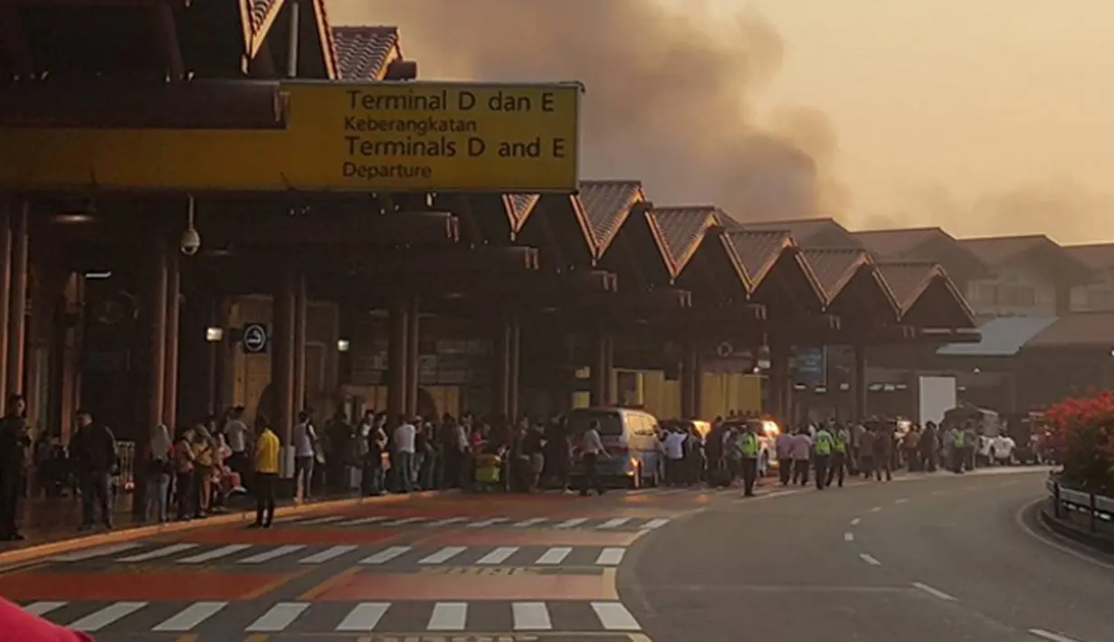 Sejumlah penumpang melihat kebakaran yang terjadi di Terminal 2E di Bandara Soekarno Hatta, Jakarta, Minggu (5/7/2015).  Kebakaran di Terminal 2E ini membuat panik ribuan penumpang yang sedang menunggu jadwal penerbangan. (Twitter@avgustin88)