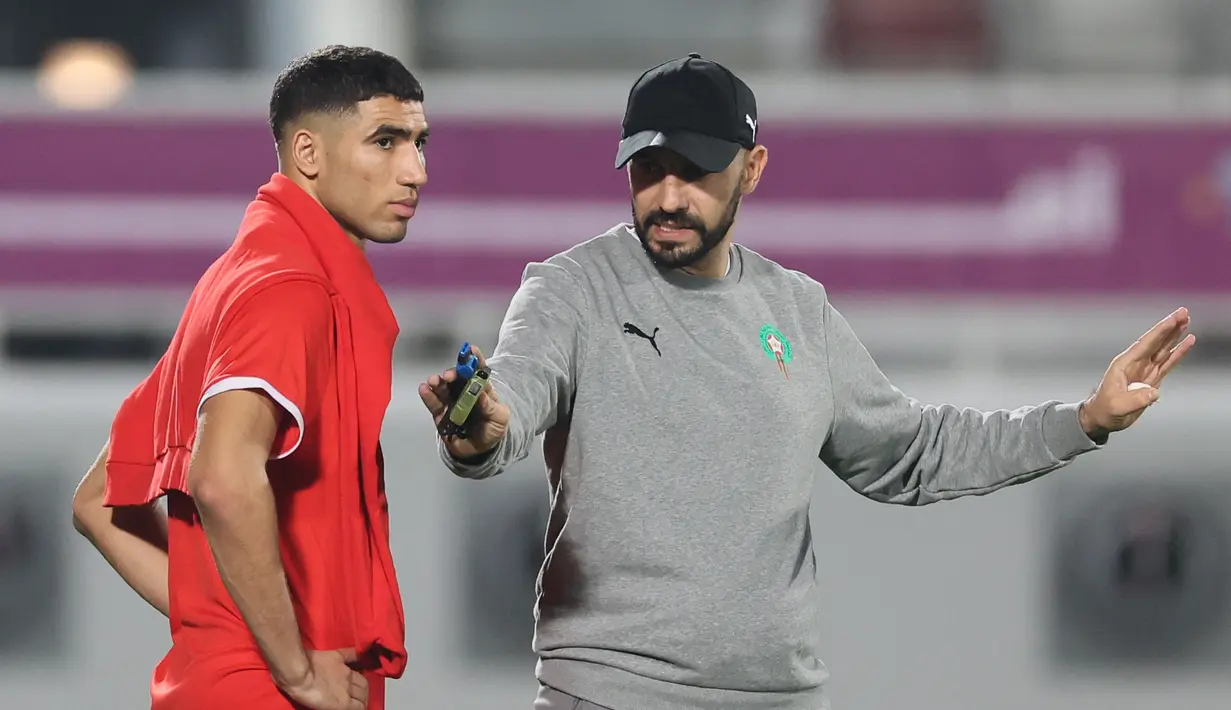 Bek Maroko, Achraf Hakimi mendengarkan pelatih Walid Reragui selama sesi latihan jelang menghadapi Prancsi di babak semifinal Piala Dunia 2022  di Stadion Al Duhail SC di Doha pada 13 Desember 2022. Maroko berhasil lolos ke semifinal usai menyingkirkan Portugal dengan skor 1-0 pada babak perempat final. (AFP/Karim Jaafar)