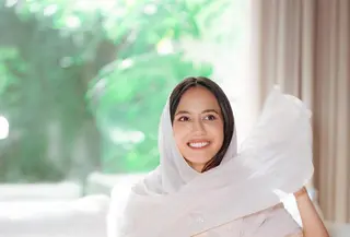Penampilan Pevita Pearce di foto ini bisa kamu jadikan inspirasi outfit bukber. Ia tampil mengenakan gamis lengan pendek yang mengkilap, menambah nuansa mewah pada tampilan yang sederhana. Pevita menambahkan selendang putih polos untuk menutupi kepalanya. [Foto: Instagram/pevpearce]
