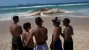 Sejumlah remaja mengamati bangkai paus bungkuk di tepi pantai Ipanema, Rio de Janeiro, Brasil, Rabu (15/11). Paus tersebut memiliki panjang sekitar 12 meter dan berat 25 ton atau 25 ribu kilogram. (AP/Silvia Izquierdo)