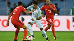 Pemain Timnas Inggris U-17, Jadon Sancho (tengah) berusaha melewati adangan pemain Chile, Gaston Zuniga (kiri) pada laga Grup F Piala Dunia U-17 2017 di Salt Lake Stadium, Kolkata, India, 8 Oktober 2017. Sancho tercatat mencetak 3 gol sepanjang turnamen tersebut. (AFP/Dibyangshu Sarkar)