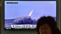 Seorang wanita melewati layar yang menyiarkan berita tentang peluncuran roket Korut, di stasiun kereta di Seoul, Korsel, Jumat (4/3). Kim Jong-Un memerintahkan pasukannya menyiagakan senjata nuklir untuk bisa digunakan kapan saja. (AFP PHOTO/Jung YEON-JE)
