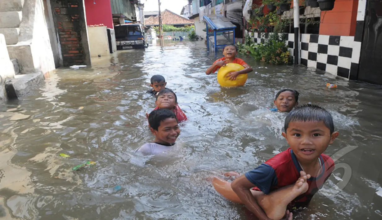 Hujan yang mengguyur Jakarta sejak Minggu (8/2) lalu, membuat Waduk Ria Rio meluap. Para bocah ini asyik bermain saat bajir melanda kawasan rumah mereka di Pendongkelan, Jakarta, Selasa (10/2/2015). (Liputan6.com/Herman Zakharia)