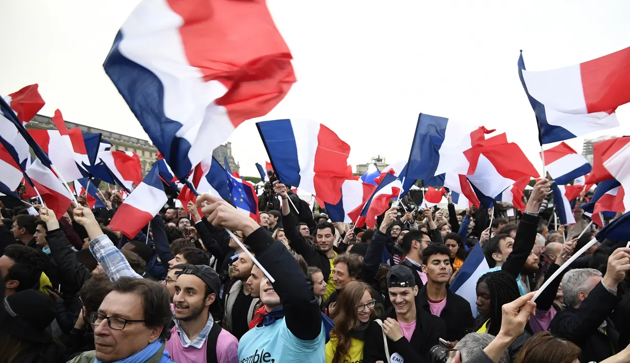 Pendukung mengibarkan bendera Prancis saat merayakan kemenangan Emmanuel Macron di luar museum Louvre, Paris, Minggu (7/5). Berdasarkan exit poll sejauh ini, rakyat Prancis memilih Macron sebagai presiden mereka yang baru. (AFP PHOTO/Eric FEFERBERG)