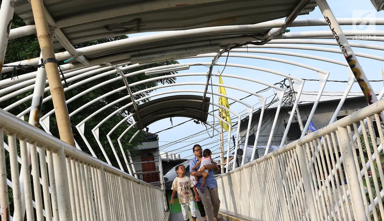 Pejalan kaki melintasi jembatan penyeberangan orang (JPO) Jayakarta yang atapnya rusak dan hilang di Menteng, Jakarta, Jumat (11/1). Kondisi atap JPO yang rusak akibat tertiup angin mengganggu kenyamanan pejalan kaki. (Liputan6.com/Immanuel Antonius)
