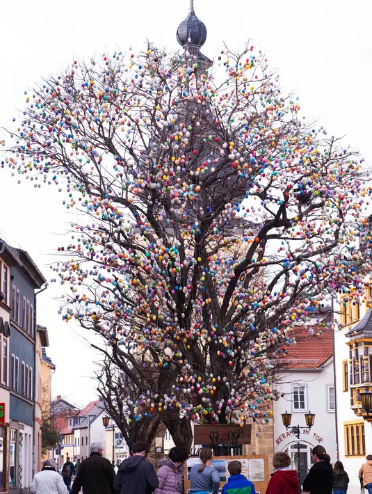 Pengunjung berdiri di depan pohon robinia berhias 10.000 telur paskah warna-warni di Saalfeld, Jerman, Jumat (30/3). Pohon Paskah, merupakan tradisi lain yang berumur berabad-abad dan dibuat dari pohon atau semak kecil yang masih hidup. (AP/Jens Meyer)