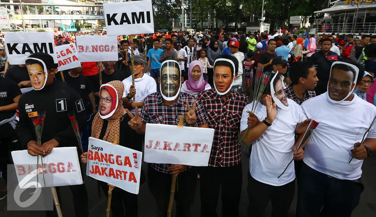 Relawan mengenakan topeng dan atribut tiga paslon Cagub/Cawagub DKI Jakarta melakukan aksi kampanye pilkada damai, aman dan sportif di CFD, kawasan Bunderan HI, Jakarta, Minggu (30/10). (Liputan6.com/Johan Tallo)