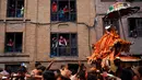 Warga menonton arak-arakan kereta Dewa dalam perayaan sindoor Jatra festival di Bhaktapur, Nepal (15/4). Mereka bermain drum tradisional sambil bernyanyi dan menari. (AP Photo/Niranjan Shrestha)